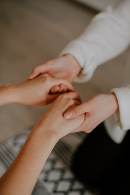 Duas pessoas de mãos dadas, em um gesto de apoio e cuidado.